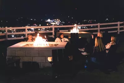 Sitting around fire pit at SkyLand Ranch with city lights in background