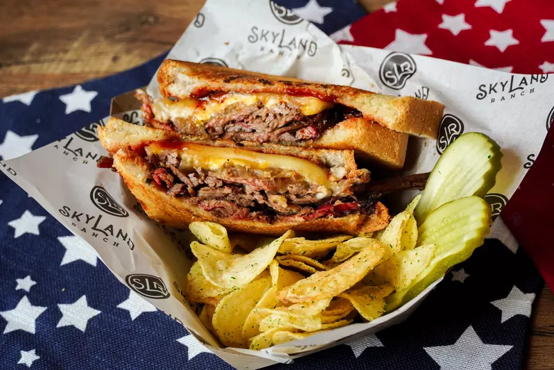 brisket sandwich with chips and pickles
